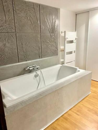 Cette chambre dispose de parquet et d'une baignoire blanche. dans l'établissement Le Loft du Petit Four, à Reims