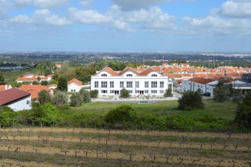 a large white building with red roofs on a green field at Quinta do Piloto in Palmela