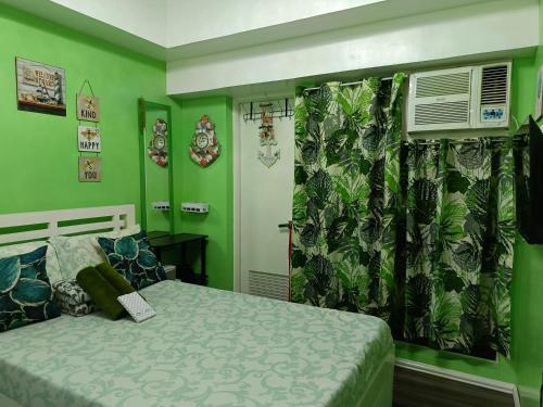 a bedroom with green walls and a bed and a window at Uncle's Tagaytay Staycation in Iruhin