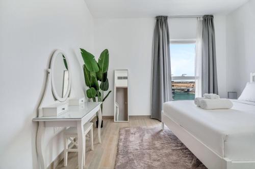 a white bedroom with a white bed and a mirror at Yas Escape -2BR by SLV in Abu Dhabi