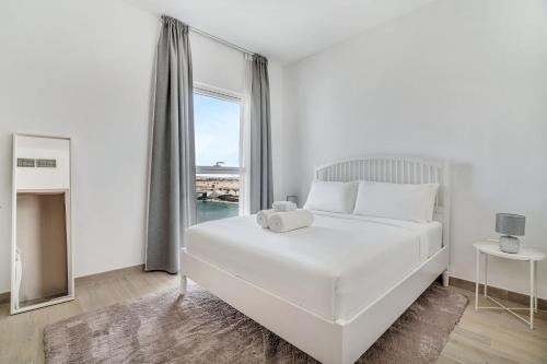a white bedroom with a large bed and a window at Yas Escape -2BR by SLV in Abu Dhabi