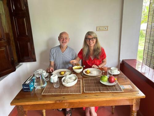a man and a woman sitting at a table with food at Gramam Homestay, Cochin in Cochin