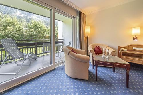 a room with a balcony with chairs and a table at EUROPÄISCHER HOF Bad Gastein in Bad Gastein