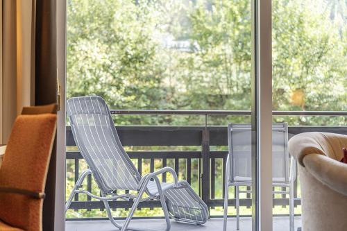 two chairs sitting on a balcony looking out the window at EUROPÄISCHER HOF Bad Gastein in Bad Gastein