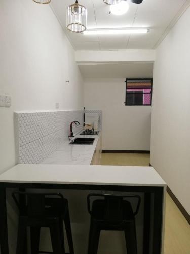 a kitchen with a white counter and two stools at casa610 HOMESTAY PD in Port Dickson