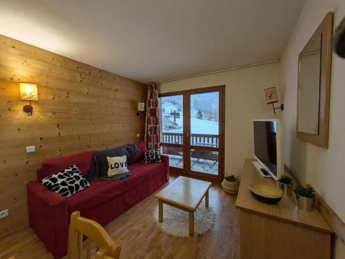 ein Wohnzimmer mit einem roten Sofa und einem TV in der Unterkunft Lumière des Neiges - 6 pers - 2 SDB - 1 terrasse - Pieds des pistes in Valmeinier
