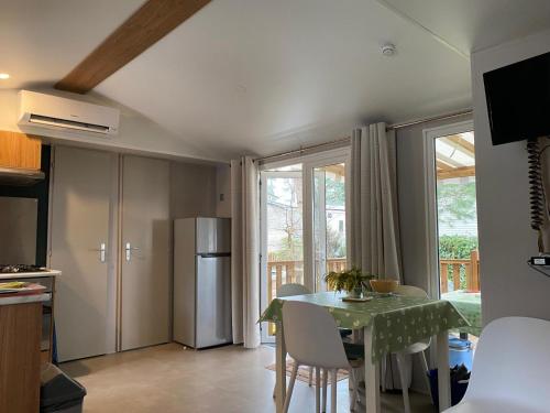 une cuisine et une salle à manger avec une table et un réfrigérateur dans l'établissement MH 084 MAGNIFIQUE 2ch et 2sdb dont suite parentale au calme dans camping 4étoiles, à Saint-Julien-en-Born