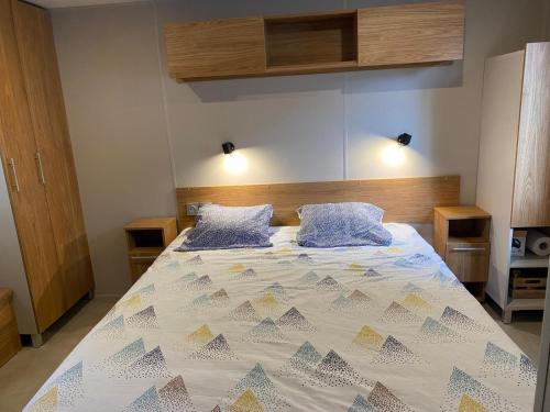 - une chambre avec un grand lit et 2 oreillers bleus dans l'établissement MH 084 MAGNIFIQUE 2ch et 2sdb dont suite parentale au calme dans camping 4étoiles, à Saint-Julien-en-Born