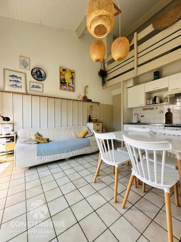 un salon avec un canapé, une table et des chaises dans l'établissement Maison de vacances à 150m de la plage - la Loubine, à La Tremblade