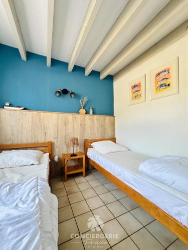 deux lits dans une chambre aux murs bleus dans l'établissement Maison de vacances à 150m de la plage - la Loubine, à La Tremblade
