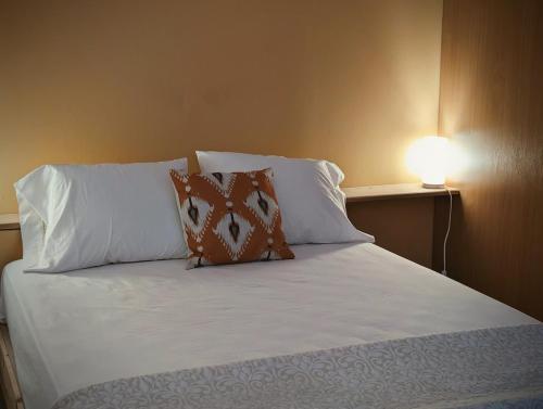 a bed with white pillows and a lamp on a wall at SeafrontView - Cozy T1 Apartment 2 in Praia