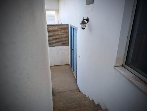 an empty hallway with a blue door and a window at SeafrontView - Cozy T1 Apartment 2 in Praia