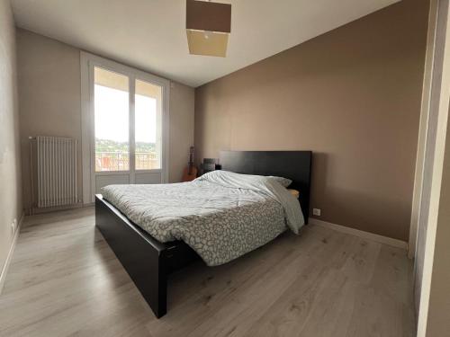 une chambre avec un lit et une grande fenêtre dans l'établissement Bel appartement avec vue sur les monuments Ponot, à Espaly-Saint-Marcel