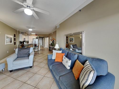 un salon avec un canapé bleu et deux chaises dans l'établissement Tidewater #108, à Orange Beach