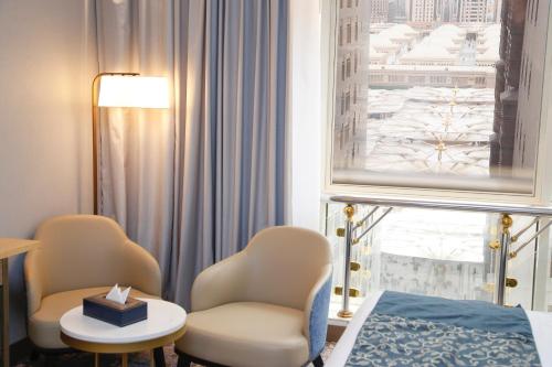 a room with a bed and two chairs and a window at MADEN Al Rawda مادن الروضة in Al Madinah