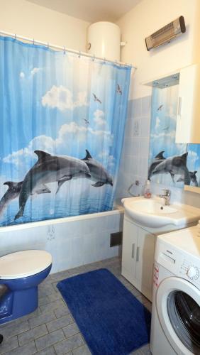 a bathroom with dolphins in a shower curtain at Apartment Beky in Podstrana