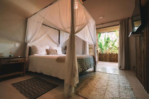 a bedroom with a canopy bed and a window at Pousada Awêry Caraíva in Caraíva