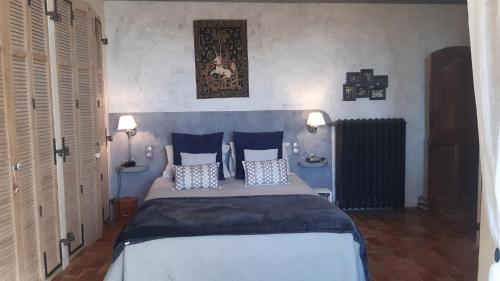 une chambre avec un grand lit avec des oreillers bleus dans l'établissement Le Midi, A Refined Master House in Provence with a swimming pool, à Valensole