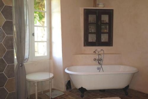 La salle de bains est pourvue d'une baignoire, d'une fenêtre et d'un tabouret. dans l'établissement Le Midi, A Refined Master House in Provence with a swimming pool, à Valensole