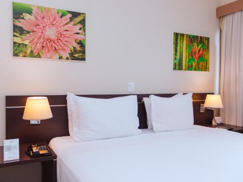 two beds in a hotel room with two lamps at Hotel Saint Paul in Manaus