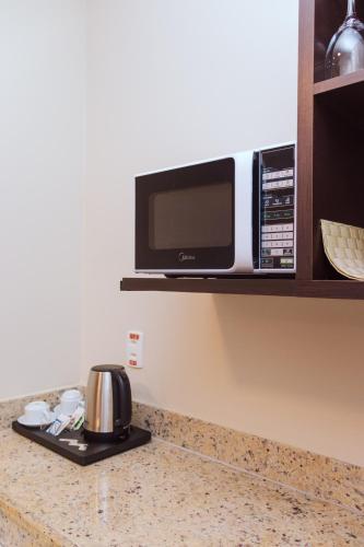 a microwave sitting on a shelf above a kitchen counter at Hotel Saint Paul in Manaus