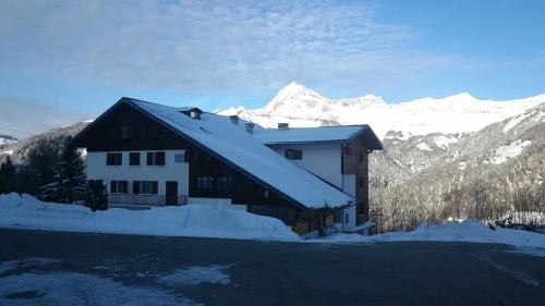 une maison couverte de neige avec des montagnes en arrière-plan dans l'établissement Centre de vacances Les Pieux, à Crest-Voland