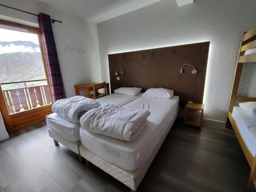 une chambre avec un grand lit et une grande fenêtre dans l'établissement Centre de vacances Les Pieux, à Crest-Voland