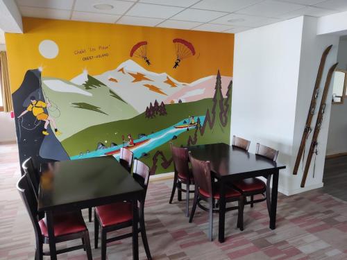 une salle à manger avec une table et des chaises ornée d'une fresque murale de montagne. dans l'établissement Centre de vacances Les Pieux, à Crest-Voland