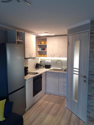a kitchen with white cabinets and a sink and a refrigerator at Művészház Nyaraló in Békésszentandrás