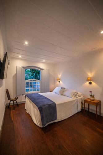 a bedroom with a large bed and a window at Casa Odara Paraty in Paraty