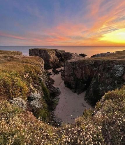 - un coucher de soleil sur une plage avec des rochers et l'océan dans l'établissement Charmante maison familiale au Pouliguen, au Pouliguen