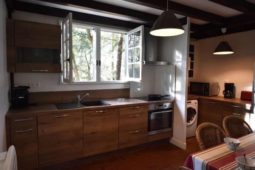 une cuisine avec des armoires en bois, un évier et une fenêtre dans l'établissement Hossegor « La landaise » Belle villa landaise pour 6 personnes., à Hossegor