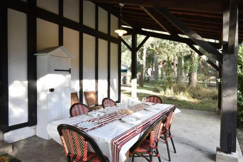 une table avec des chaises rouges et un tissu de table blanc dans l'établissement Hossegor « La landaise » Belle villa landaise pour 6 personnes., à Hossegor