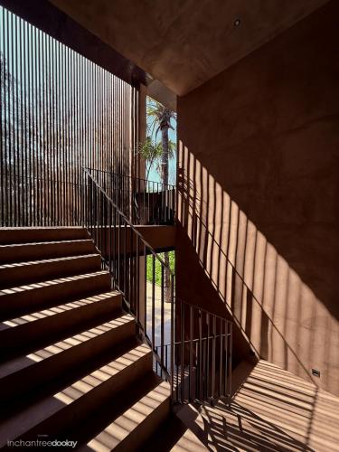 a staircase in a building with shadows on the wall at inchantreedoolay huahin in Pran Buri