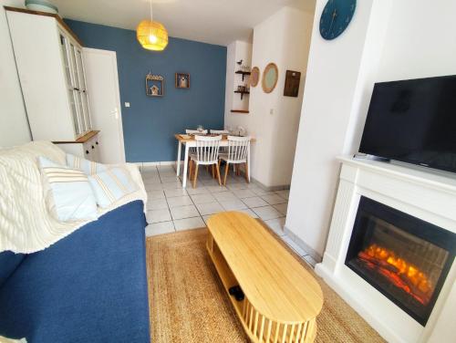 un salon avec une cheminée et une table dans l'établissement Entre mer et golf Appartement en rez de jardin avec parking, à Fort-Mahon-Plage