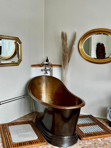 a copper tub in a bathroom with a mirror at Hotell Dannegården in Trelleborg