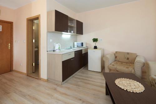 a kitchen and a living room with a couch and a table at Apart Hotel Vechna R in Sunny Beach