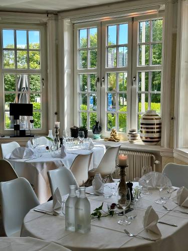 a restaurant with white tables and white chairs and windows at Hotell Dannegården in Trelleborg