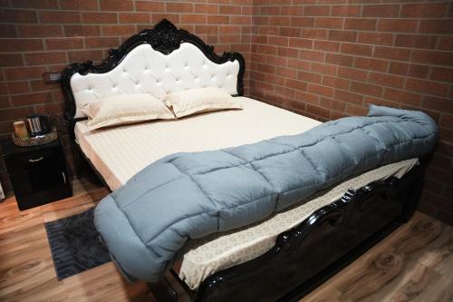 a bed with a blue blanket and a brick wall at Digaru Air House in Digru