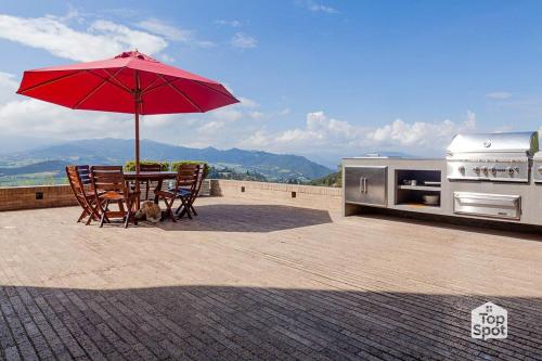 a patio with a table and an umbrella and a grill at TopSpot with Super View in the Guasca Mountains in Cundinamarca