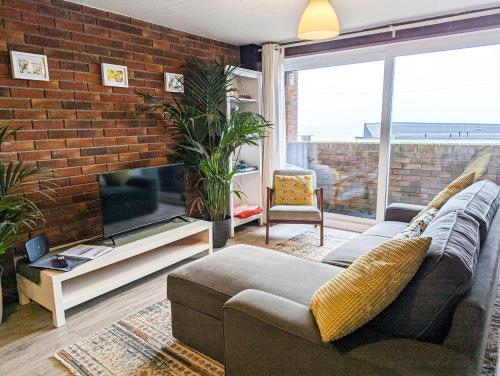a living room with a couch and a brick wall at South Fistral View Apartment in Newquay