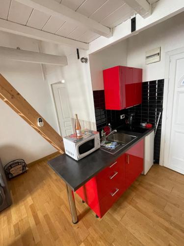 une cuisine avec des placards rouges et un four micro-ondes sur un comptoir dans l'établissement Studio centre ville à 5min plages, palais et gare, à Cannes