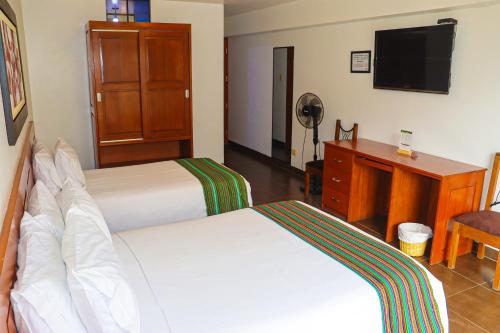 a hotel room with two beds and a desk and a television at Kankay Hotel y Centro de Convenciones in Cieneguilla