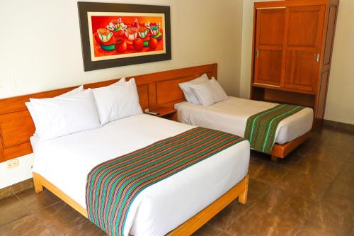 a hotel room with two beds and a painting on the wall at Kankay Hotel y Centro de Convenciones in Cieneguilla