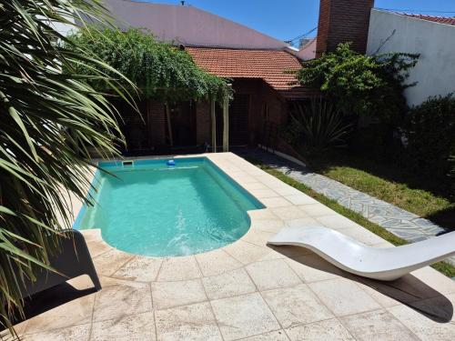 a swimming pool with a white chair next to a house at Chalet Tucumán in Bahía Blanca