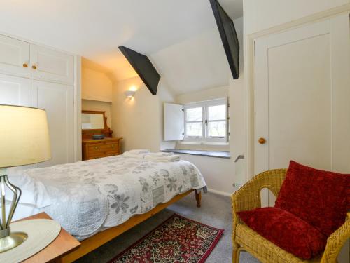 ein Schlafzimmer mit einem Bett, einem Stuhl und einem Tisch in der Unterkunft Churchgate Cottage in Bodmin