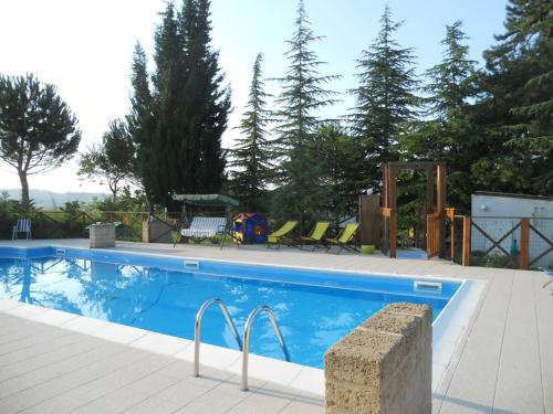 a swimming pool with chairs and trees in the background at Agriturismo Il Palmarone in Rotella