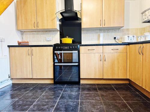 a kitchen with wooden cabinets and an oven at Immaculate Haven in Westhoughton