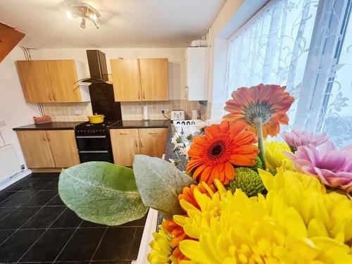 a kitchen with a bunch of colorful flowers on a counter at Immaculate Haven in Westhoughton