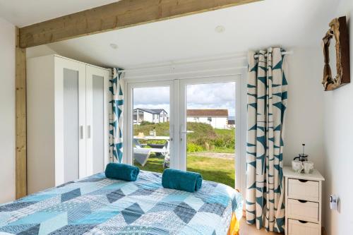 a bedroom with a bed and a large window at WestHill Beach Chalet, Riviere Towans in Hayle